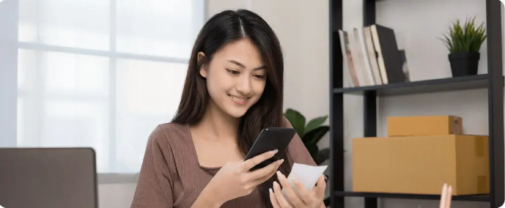Smiling asian woman looking at smartphone